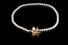 COLLAR DE PERLAS De una vuelta de perlas cultivadas, calibradas en 5.5 mm. Con cierre realizado en oro amarillo de 18 kt. en forma de flor, con un rubí (lascado), un zafiro y una esmeralda engastados en chatón en la parte central.