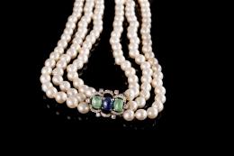 COLLAR DE PERLAS De tres vueltas formado por perlas cultivadas calibradas entre 8 y 10 mm. Broche calado realizado en oro blanco de 18 kt., compuesto por 2 esmeraldas y un zafiro (lascado) talla cabujón engastados en garras, orlados por 36 diamantes talla