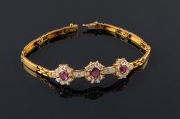 PULSERA Realizada en oro, compuesta por tres rosetas formadas por tres rubíes talla oval orlados y acompañados por piedras de imitación. 