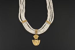 GARGANTILLA Realizada en oro amarillo de 18k, compuesta por cuatro hilos de perlas cultivadas calibradas en 5mm., unidas entre sí por placas con runas labradas en oro amarillo de 18k, de las que pende un medallón con motivos geométricos cincelados.