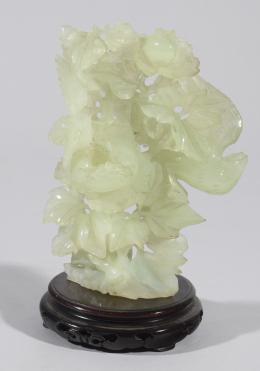 FIGURA TALLADA EN JADEITA REPRESENTANDO RÓLEOS VEGETALES Y FLORALES, SOBRE BASE DE MADERA EBONIZADA Jadeita 15 cm.x10 cm.x5 cm.