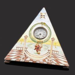 RELOJ DE SOBREMESA MASÓNICO FINALES S.XIX Realizado en latón con frente en esmalte de Viena y símbolos masónicos. Reloj en la parte superior con esfera blanca y numeración romana. Sistema de carga cuerda-llave (se adjunta llave). En estado de marcha.Medid