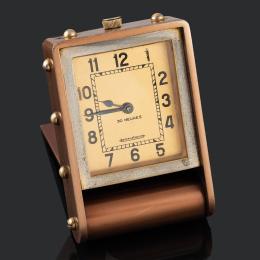 RELOJ DE SOBREMESA JAEGER LE COULTRE Realizado en metal, caja rectangular. Esfera dorada con numeración arábiga en negro, agujas pavonadas, tipo pera. Movimiento mecánico manual. Altura: 6,3 cm. En estado de marcha.