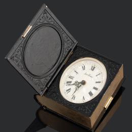 RELOJ DESPERTADOR EN FORMA DE LIBRO Realizado en metal. Esfera nacarada con numeración romana en negro, agujas tipo Luis XVI. Movimiento mecánico manual. Medidas: 7,5 x 7,5 x 3 cm. En estado de marcha.