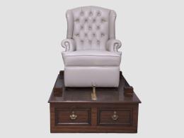 MUEBLE LIMPIA BOTAS REALIZADO A PARTIR DE UN PEDESTAL DE MADERA Y UNA BUTACA OREJERA DE PIEL TAPIZADA EN CAPITONÉ.