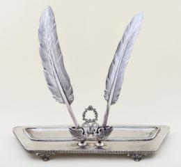 ESCRIBANÍA EN PLATA DE LEY Realizada en plata de ley, con contrastes. Con corona de motivo floral situada sobre dos cisnes, donde se encajan dos plumas con terminación en bolígrafo.