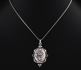 COLGANTE GUARDAPELO O GUARDAFOTO EN PLATA 916 MM Realizado en plata de 916 mm. Con motivo floral. Y cadena con cierre de reasa.