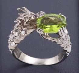 SORTIJA DRAGÓN CON PERIDOTO, CIRCONITAS Y GRANATES EN PLATA DE LEY Realizada en plata de ley, con contrastes. En forma de dragón, cuyos ojos están formados por dos granates rodolitas, destaca un peridoto en talla oval, engastado en garras, con un peso apr