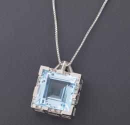 COLGANTE CON TOPACIO Y DIAMANTES EN ORO 18 KT CON CADENA EN PLATA DE LEY Realizado en oro de 18 kt, con gran topacio central en talla carré con un peso aproximado de 20.35 ct, acompañado por diamantes en talla brillante engastados en grano con un peso tot