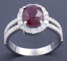 PRECIOSA SORTIJA CON RUBÍ Y DIAMANTES EN ORO 18 KT Realizada en oro de 18 kt. Formada por un gran rubí central en talla oval facetada engastado en garras, con un peso aproximado de 3.0 ct, flanqueado por una orla de diamantes en talla brillante, que conti
