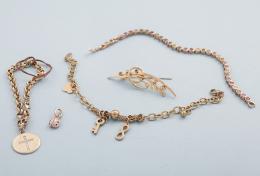 LOTE DE UN BROCHE, TRES PULSERAS Y UN COLGANTE DE METAL DORADO. broche con motivos vegetales con piedras incoloras, colgante de mariquita,pulsera con charm de cruz con piedras incoloras, pulsera con varios charms y pulsera con corazones y pulsera estilo r