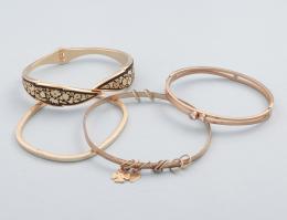LOTE DE CUATRO PULSERAS RÍGIDAS EN METAL DORADO. conjunto de cuatro pulseras rígidas en metal dorado, pulsera con decoración vegetal en fondo negro, pulsera con dos piedras incoloras, pulsera con charms y pulsera articulada.