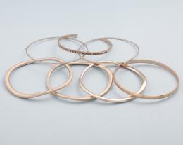 LOTE DE SIETE PULSERAS RÍGIDAS EN METAL DORADO. conjunto de siete pulseras rígidas en metal dorado, dos pulseras con piedras incoloras, tres estilo irregular, una con inscripción "I Love You To The Moon And Back" y una rígida. 