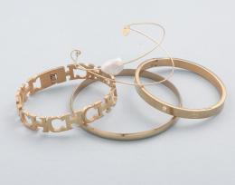LOTE DE CUATRO PULSERAS RÍGIDAS EN METAL DORADO. conjunto de cuatro pulseras rígidas en metal dorado, pulsera con perla, pulsera lisa, pulsera siguiendo modelos de "Carolina Herrera"y pulsera con piedras incoloras. 