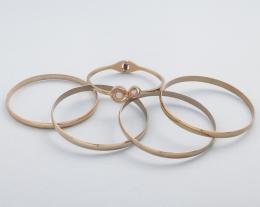 LOTE DE CINCO PULSERAS RÍGIDAS EN METAL DORADO. conjunto de cinco pulseras rígidas en metal dorado, cuatro lisas y una con piedra incolora.