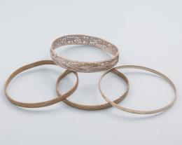 LOTE DE CUATRO PULSERAS RÍGIDAS EN METAL DORADO. conjunto de cinco pulseras rígidas en metal dorado,tres con decoraciones grabadas y una en metal plateado.