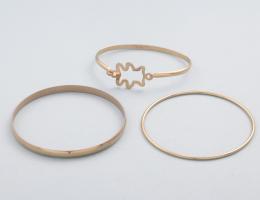 LOTE DE TRES PULSERAS RÍGIDAS EN METAL DORADO. conjunto de tres pulseras rígidas en metal dorado, dos lisas y una con silueta de un diablo.