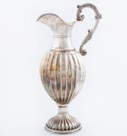 JARRO DE PLATA DE LEY Jarro de plata de cuerpo globular con decoración gallonada y asa con motivos vegetales. Con costrastes en la base.  