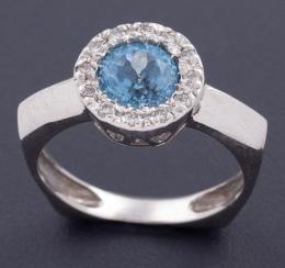 SORTIJA REALIZADA EN ORO DE 18 KT CON TOPACIO Y DIAMANTES Sortija realizada en oro de 18 kt con topacio azul central en talla redonda con orla de diamantes en talla brillante de peso total aprox 0.25 ct .