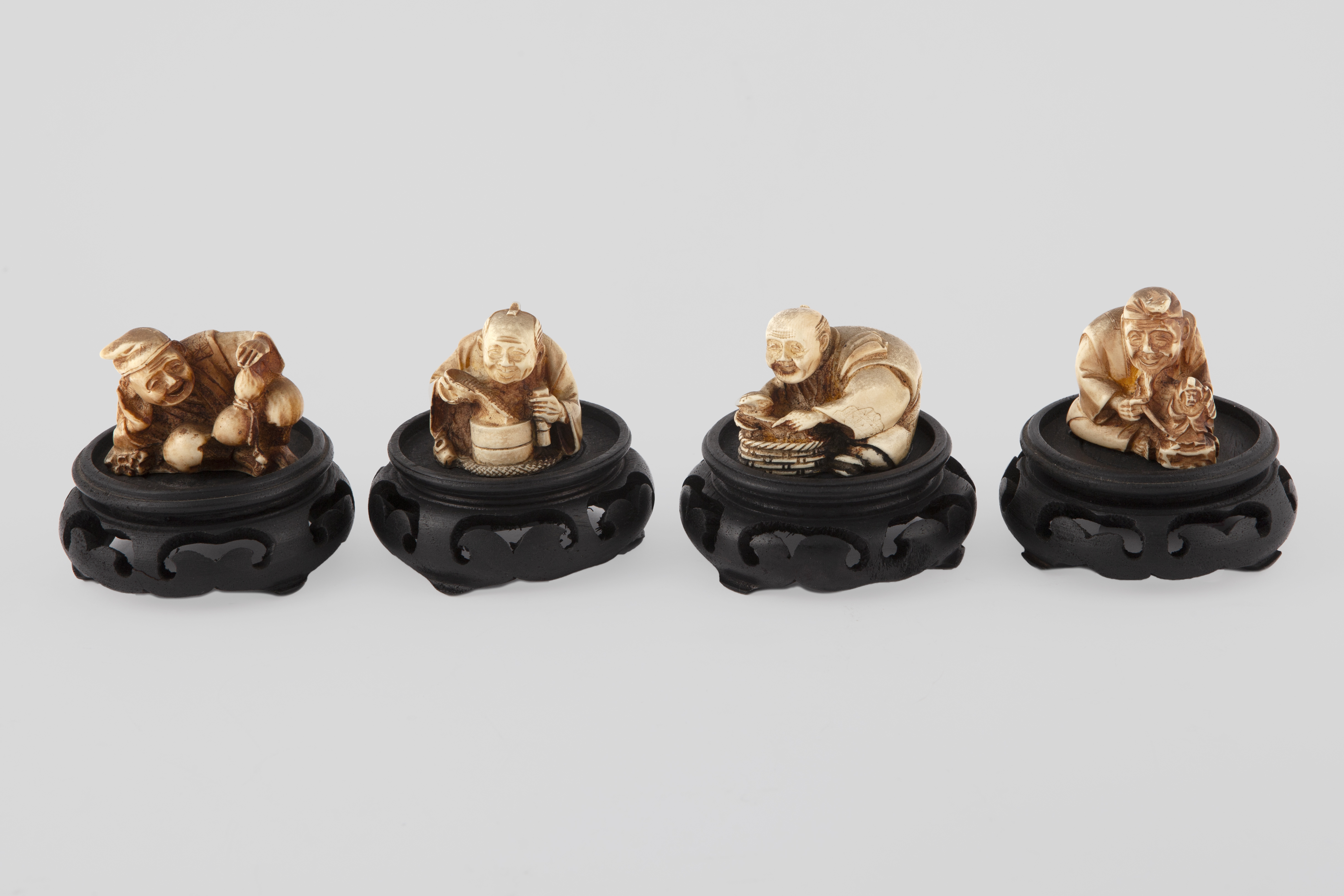 CONJUNTO DE 4 NETSUKES SOBRE PEANAS DE MADERA EBONIZADA. CH